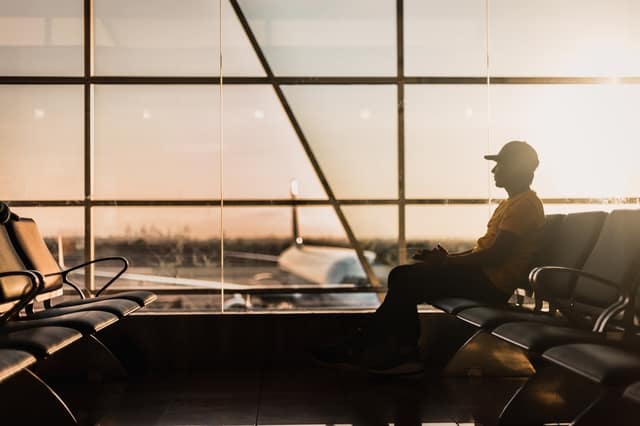 Business traveler checking a food allergy business travel checklist before boarding a flight at a busy airport terminal